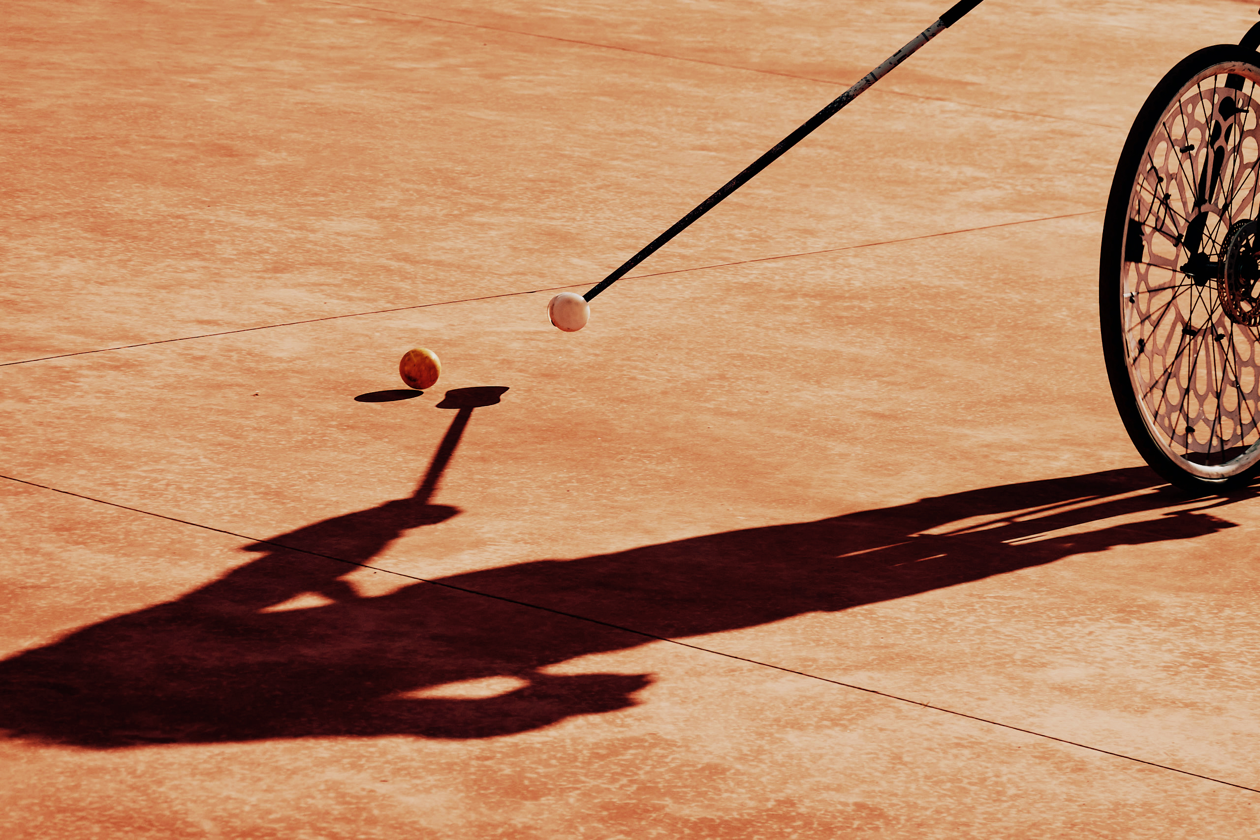 Photo d'un.e joueur.euse de bike polo en train de frapper une balle avec le grand côté de la tête de maillet.