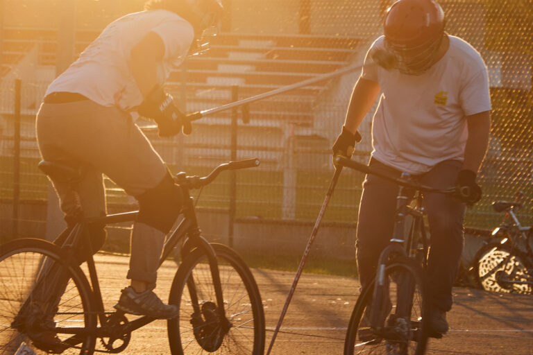 Photo d'une joueuse de bike polo en action avec la tête de son maillet à hauteur du visage de son adversaire.
